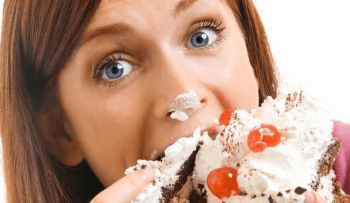 鼻にクリームを付けてケーキを食べている女性